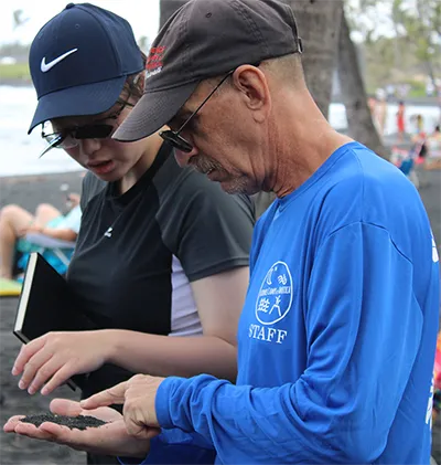 Mike discussing the geology of black sand with a student